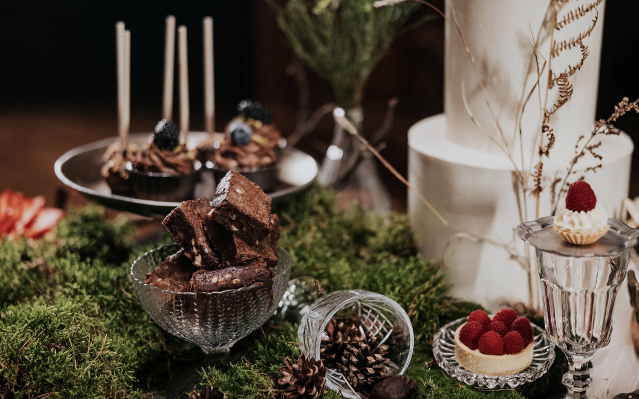 Brownie, tartaletki z malinami i słodkości na patyczkach w leśnej aranżacji